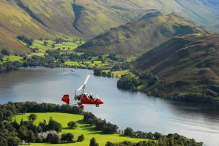 Auto gyro flying over Ullswater in the Lake District.