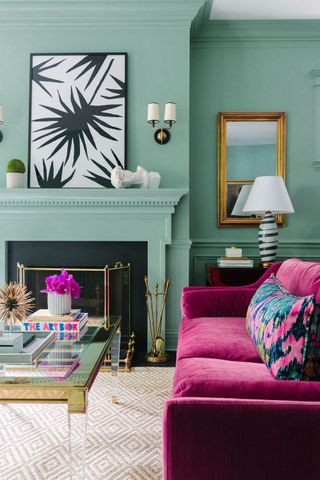 A fuchsia couch sits before a teal wall