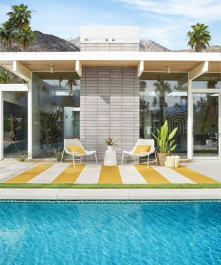 yellow and white striped rug on patio next to backyard pool