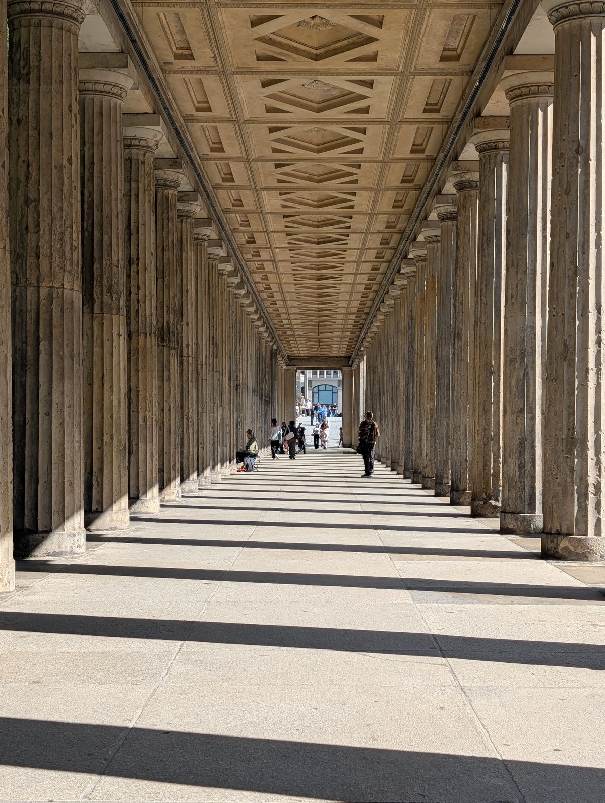 Path between large columns with the columns casting dark shadows
