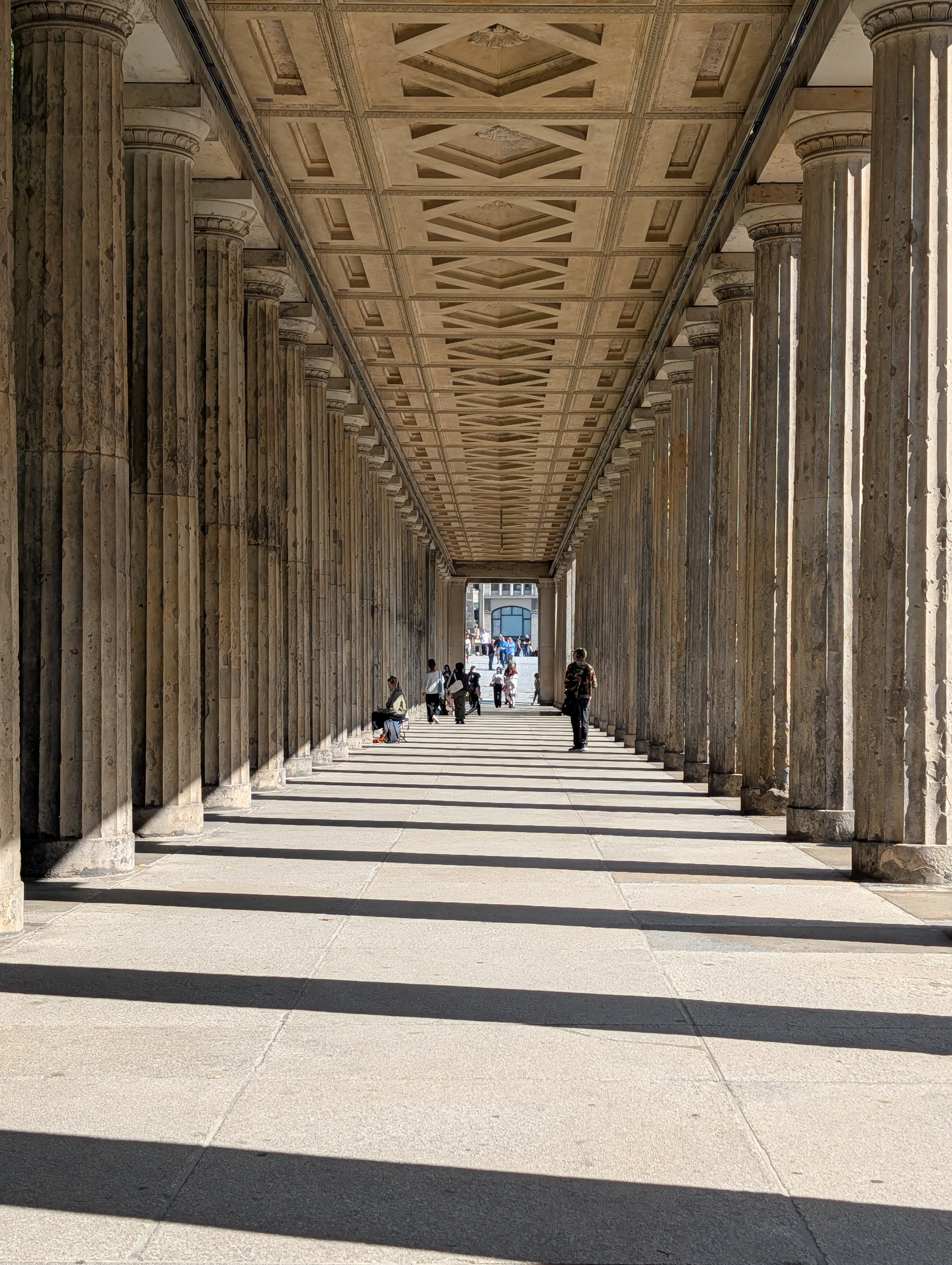 Path between large columns with the columns casting dark shadows
