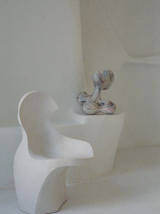 cream ceramic chair next to a multi-coloured sculpture