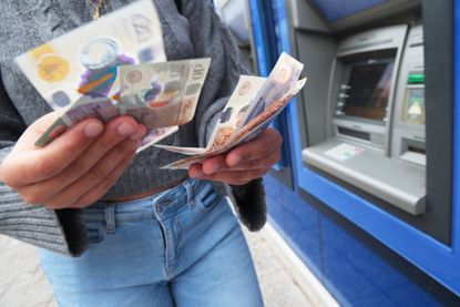 A person makes a cash deposit at a bank