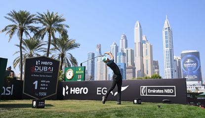Joaquin Niemann hits his tee shot off the opening hole in front of the Dubai skyline