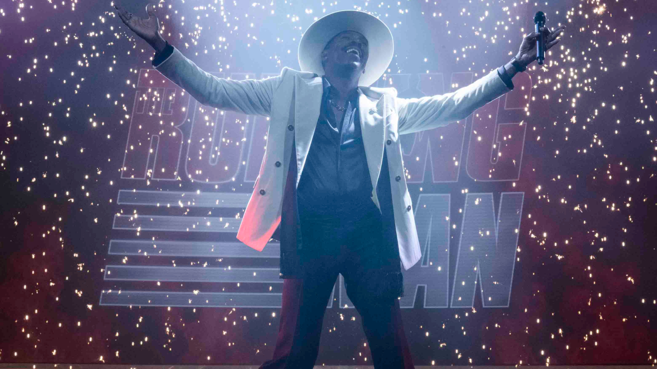 Colman Domingo stands smiling on stage in a shower of sparks in The Running Man.