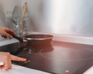 Woman using an electric stove top to cook something in a black pan