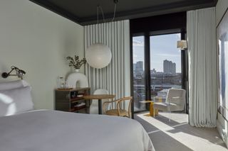 off-white hotel bedroom with white bedding and city skyline views