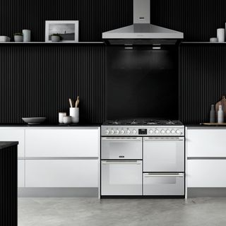 Modern white kitchen with black wall panelling and a stainless steel cooker