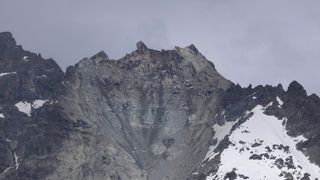 the remains of the peak of a mountain in the swiss alps , with snow covered sides and a landslide in the center