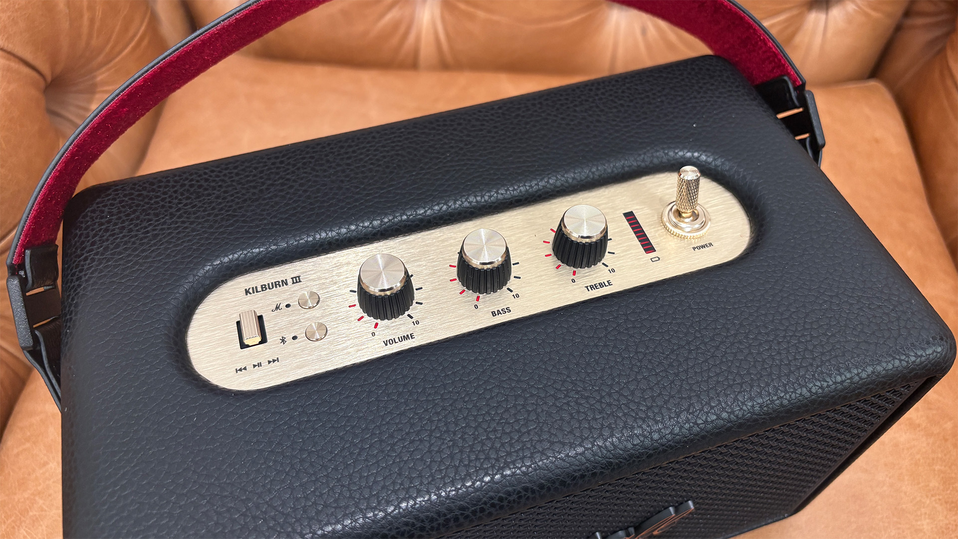 Marshall Kilburn III wireless speaker in light brown leather armchair, top of unit showing control dials