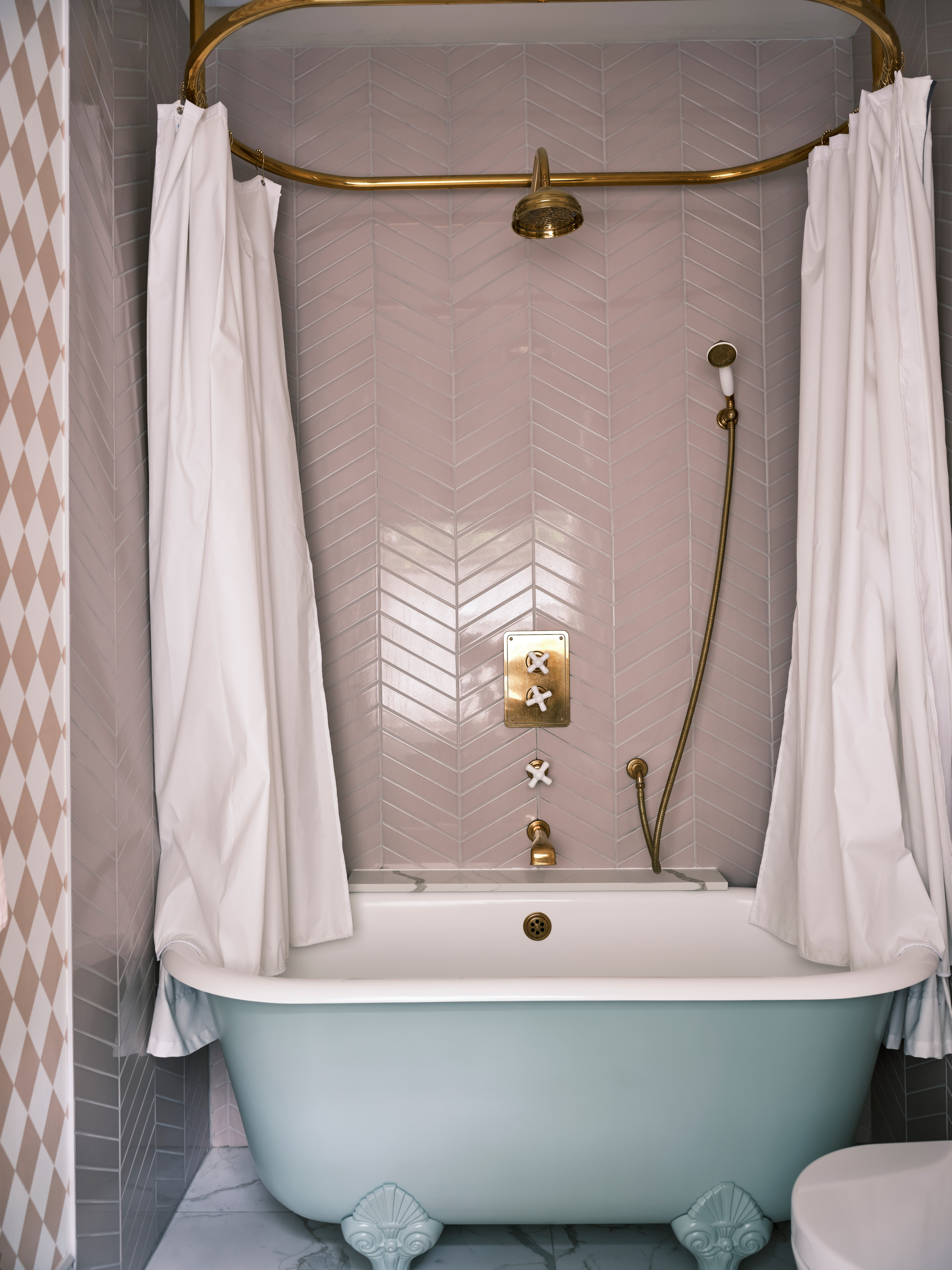 Pink bathroom with freestanding bath and herringbone tiles