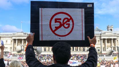 A Covid vaccine conspiracy protest, showing someone holding an anti-5G placard