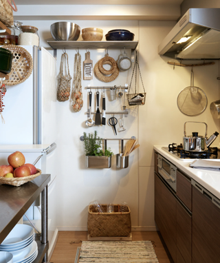 A wall in a small kitchen with various storage solutions for hanging pots, pans, kitchen utensils and more