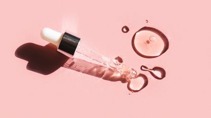Flat lay. Liquid gel or serum drop with pipette on pink background in macro. - stock photo