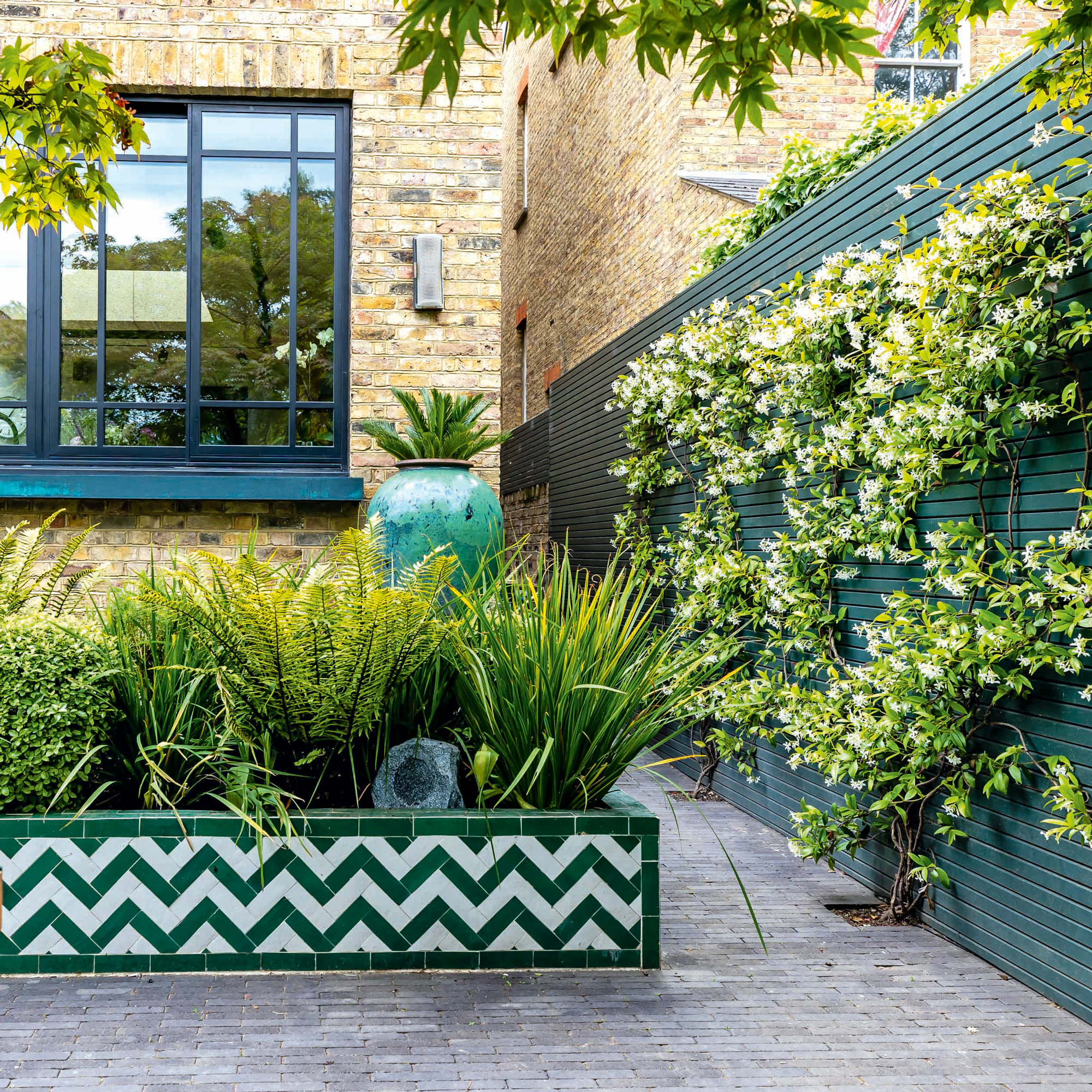 garden makeover with green fencing and patterned tiles