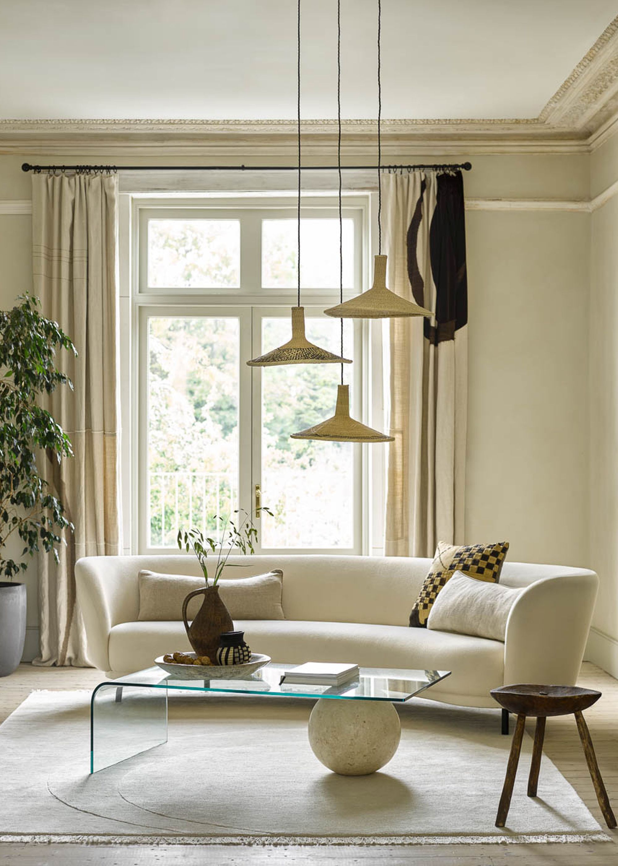 A neutral living room with cream walls and sofa, and French doors with a neutral abstract patterned curtain.