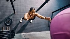 Female athlete reaching for a wall ball during a workout in a gym. High angle view of a woman performing dynamic exercise in a fitness studio