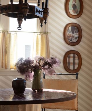 Stripey walls surround a breakfast nook with wooden picture frames and a tiled round table