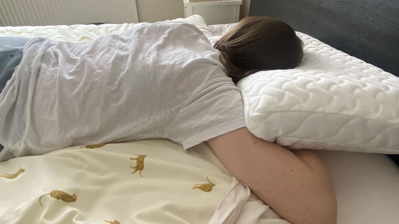 A woman lies on her stomach with her head resting on the Tempur-Pedic Tempur-Cloud pillow