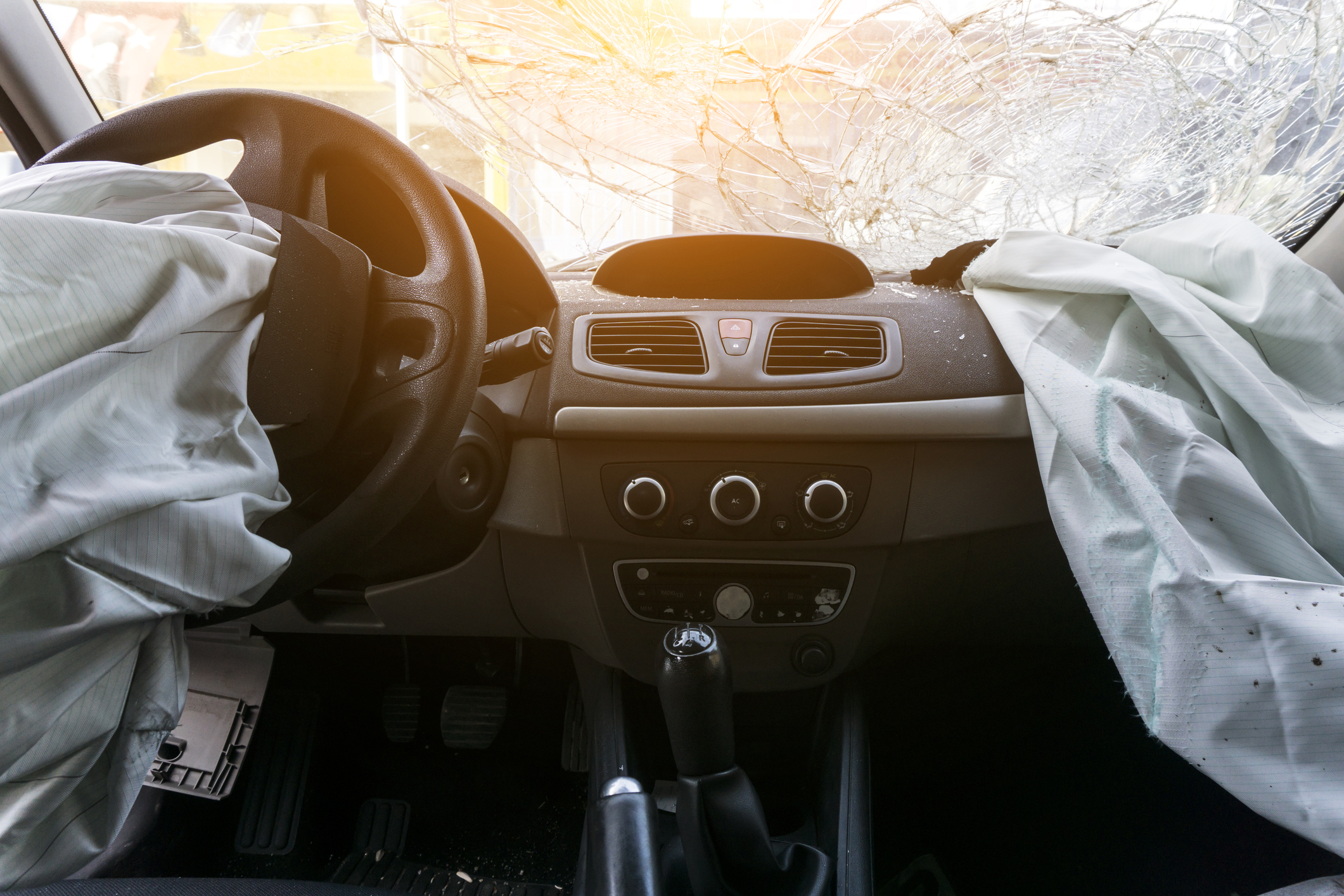 The interior of a car, with a broken windshield and deflated air bags.