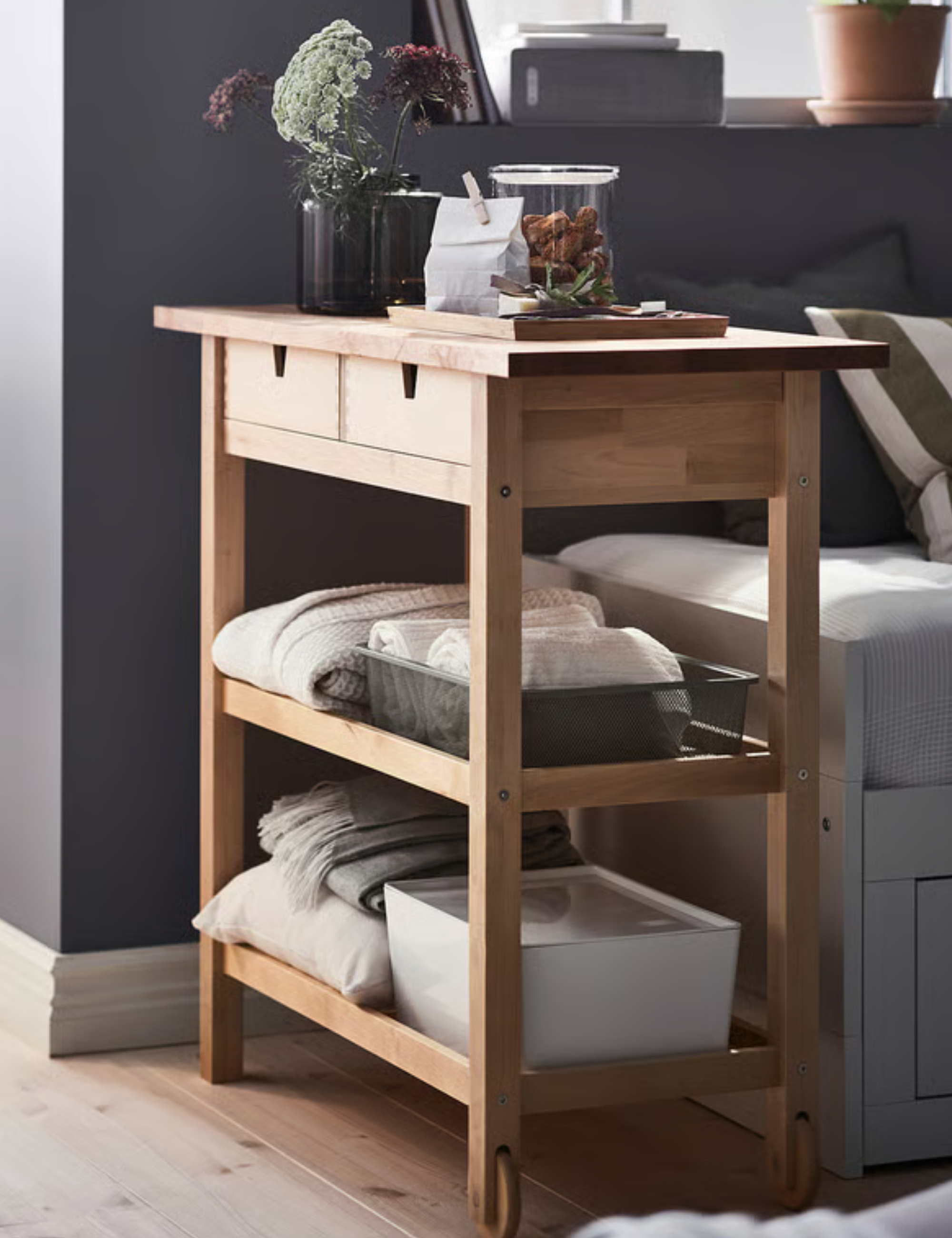 IKEA wooden trolley styled with bedding essentials in a charcoal-colored guest room