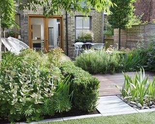 An example of small garden ideas with multiple decked terraces which weave through beds of tall plants