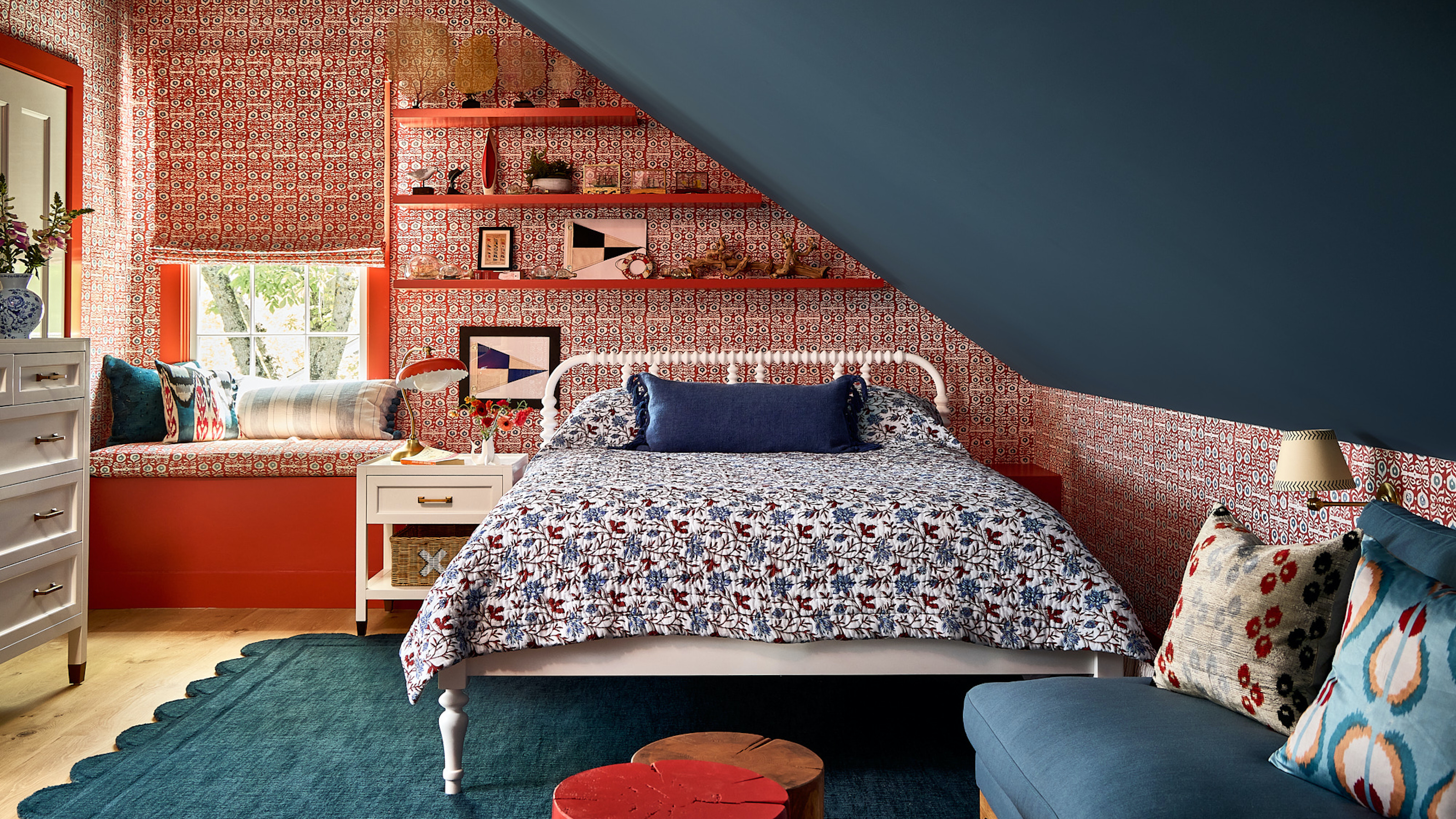 loft with bed and floating shelves, with patterned red wallpaper, and a blue painted sloped roof