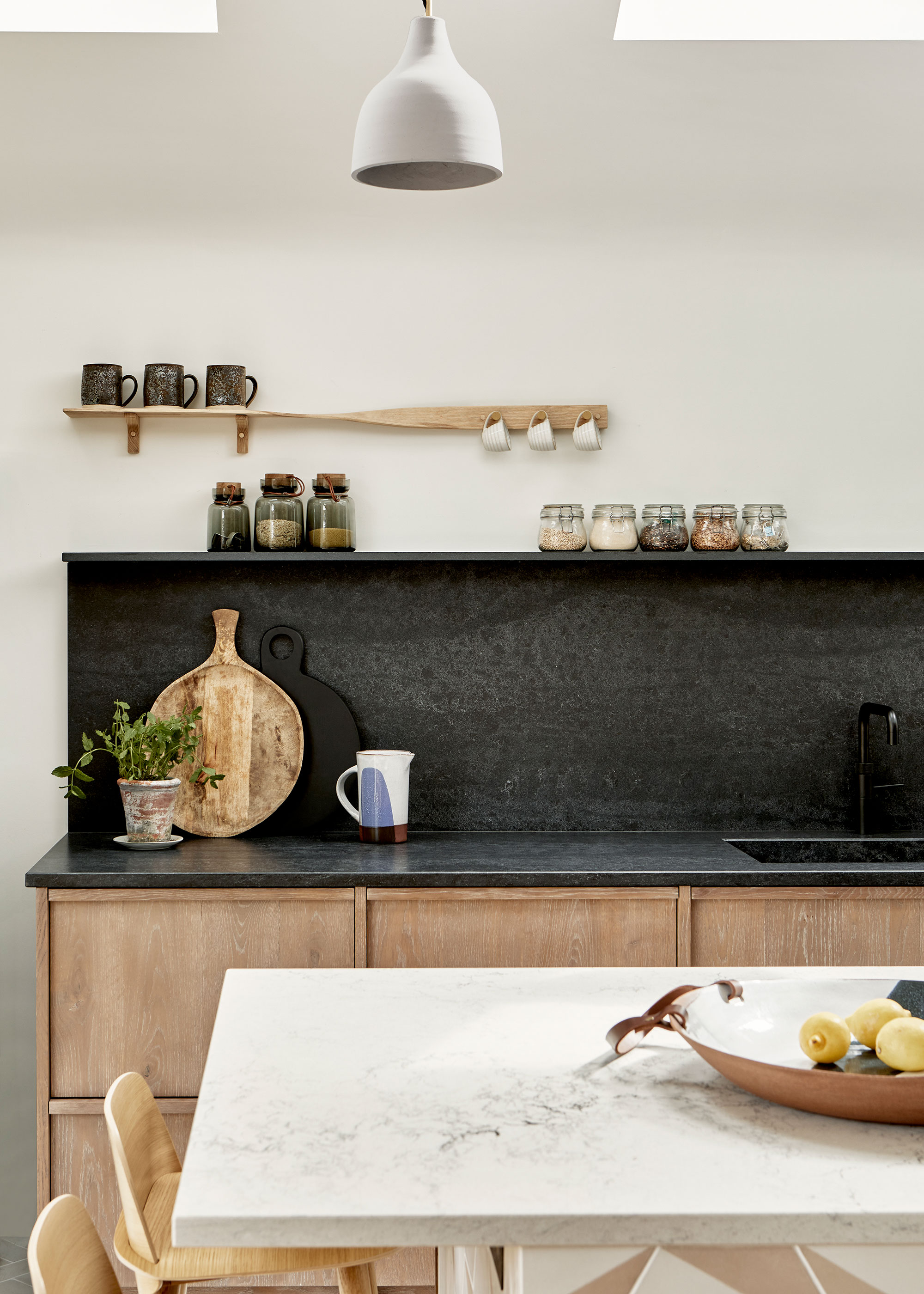 wooden kitchen with black composite work surface and splashback