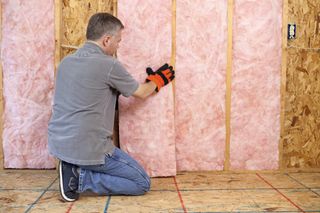 Man installing pink insulation into walls.