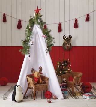 A Christmas-themed childrens' teepee with red and white shiplap wall decor