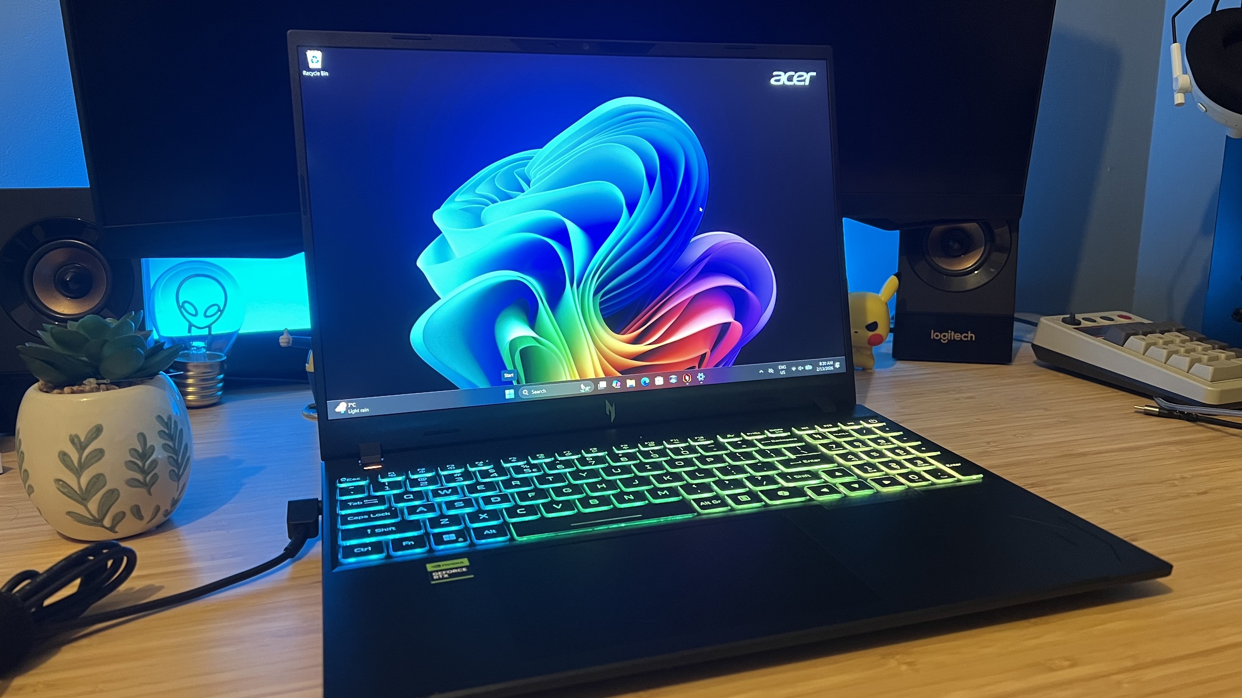 Acer Nitro V 16 AI gaming laptop on a wooden desk with blue backlighting