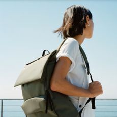 Model looking out to sea with an Everlane backpack