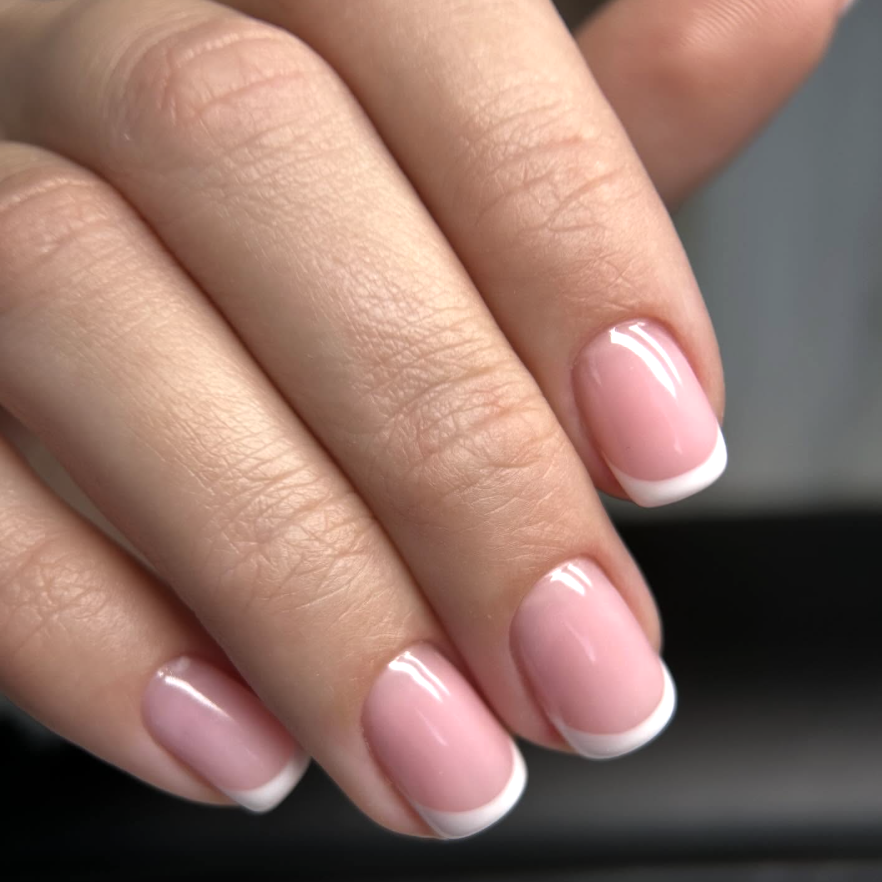 A hand with a simple milky French manicure.