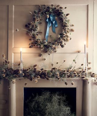 Thanksgiving wreath ideas with dried silver thistle wreath over a fireplace, where the mantel is decorated with more thistles