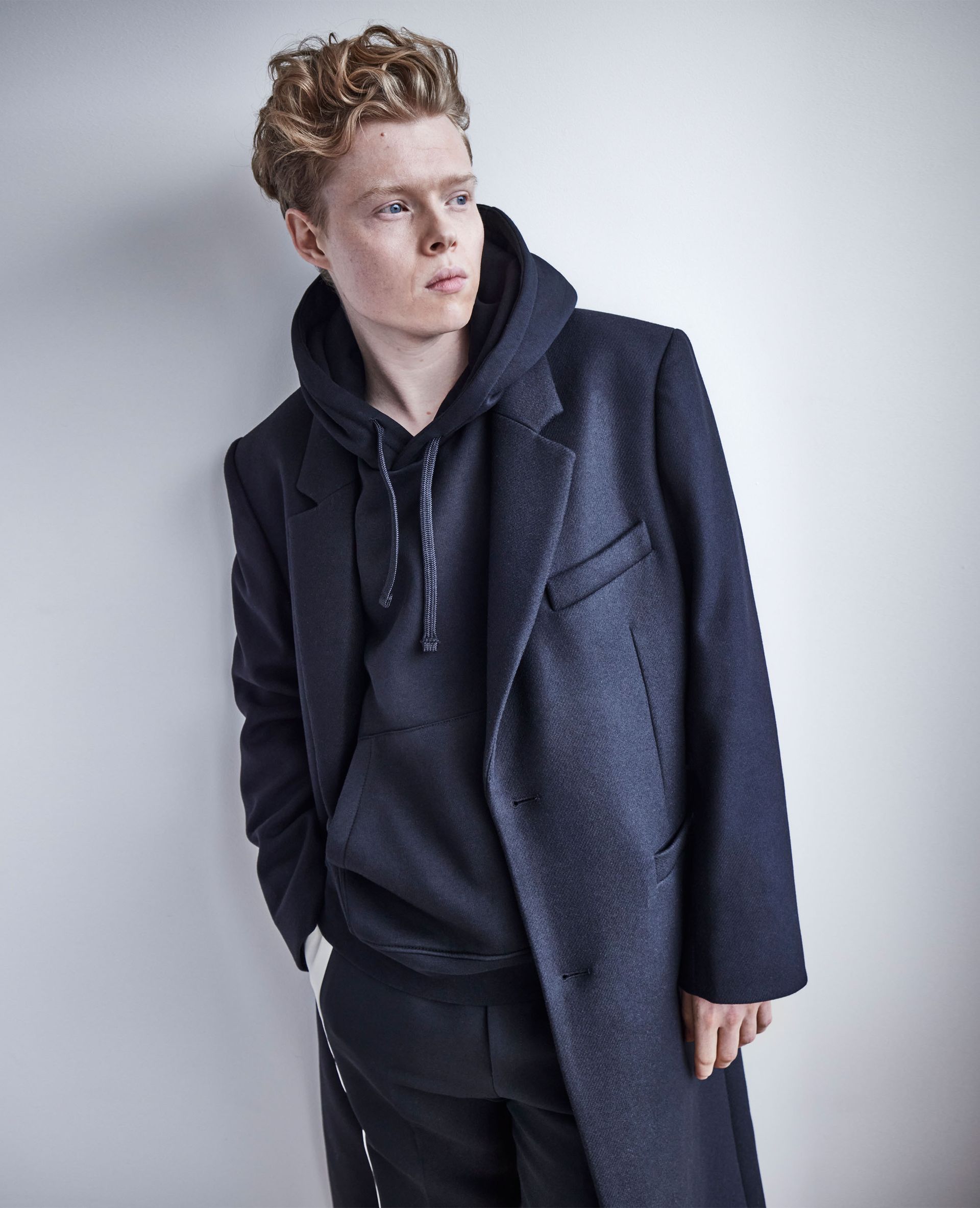 Kai Alexander wearing a navy hoodie styled with a matching blazer and pants.