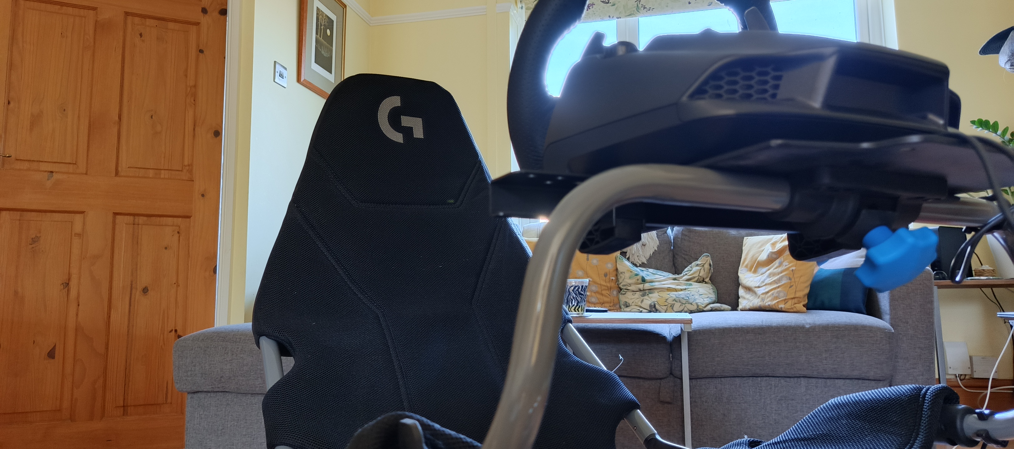 A black and grey Playseat Challenge X Logitech G Edition sim racing chair sitting in a wood-floored lounge