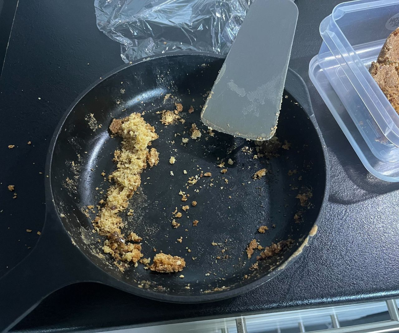 The stuck on remanents of a skillet cookie in a black cast iron pan