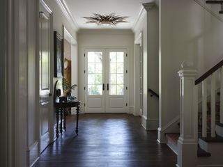 A light entryway with dark wood floors, a white door and a console table.