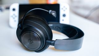 best gaming headset SteelSeries Arctic Nova Pro Wireless next to a Switch on a coffee table
