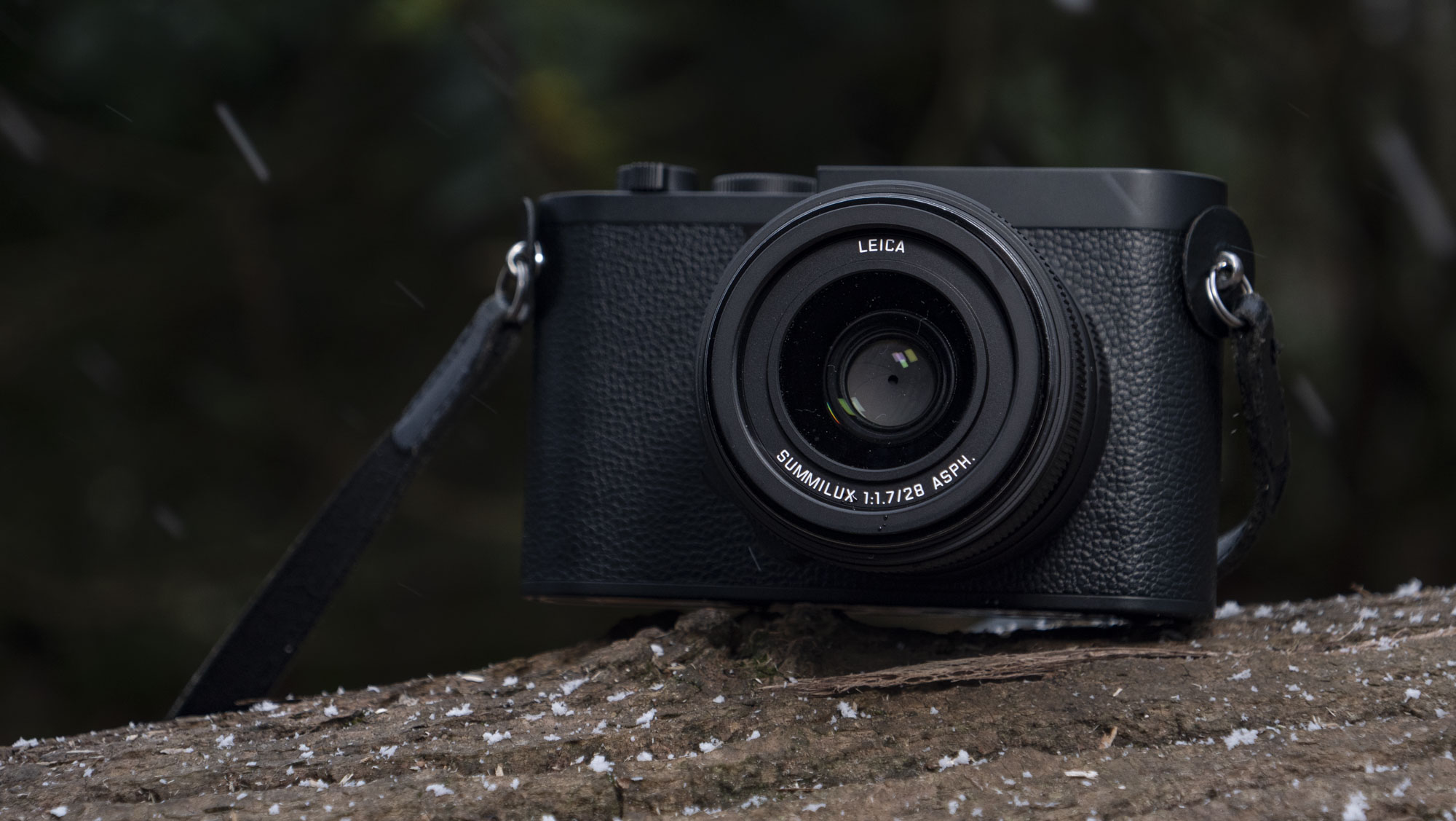 Leica Q3 Monochrom compact camera outside on a snow-dusted log