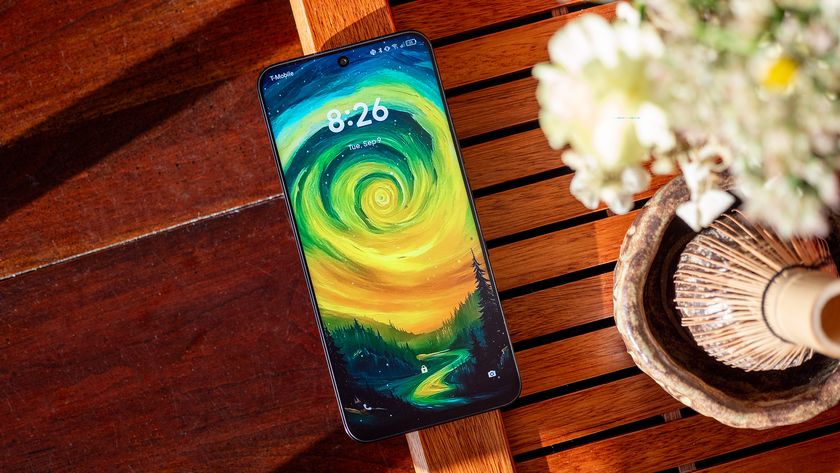 A TCL NXTPAPER 60 Ultra smartphone with a painting of a swirly sky as its wallpaper, on a tea tray with a matcha whisk and a bouquet of flowers