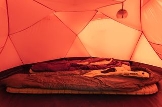 Interior view of an orange tent by 66°North and Heimplanet. There are two sleeping bags inside the tent