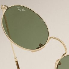 A close up of a pair of gold Ray-Ban sunglasses.