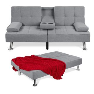 A two-seater gray couch with a folded out bed in front of it and a red throw draped over