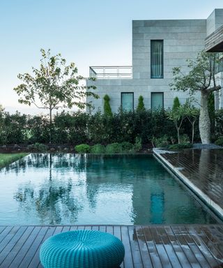 An example of pool ideas showing a stone-clad modernist house, a terrace and a swimming pool