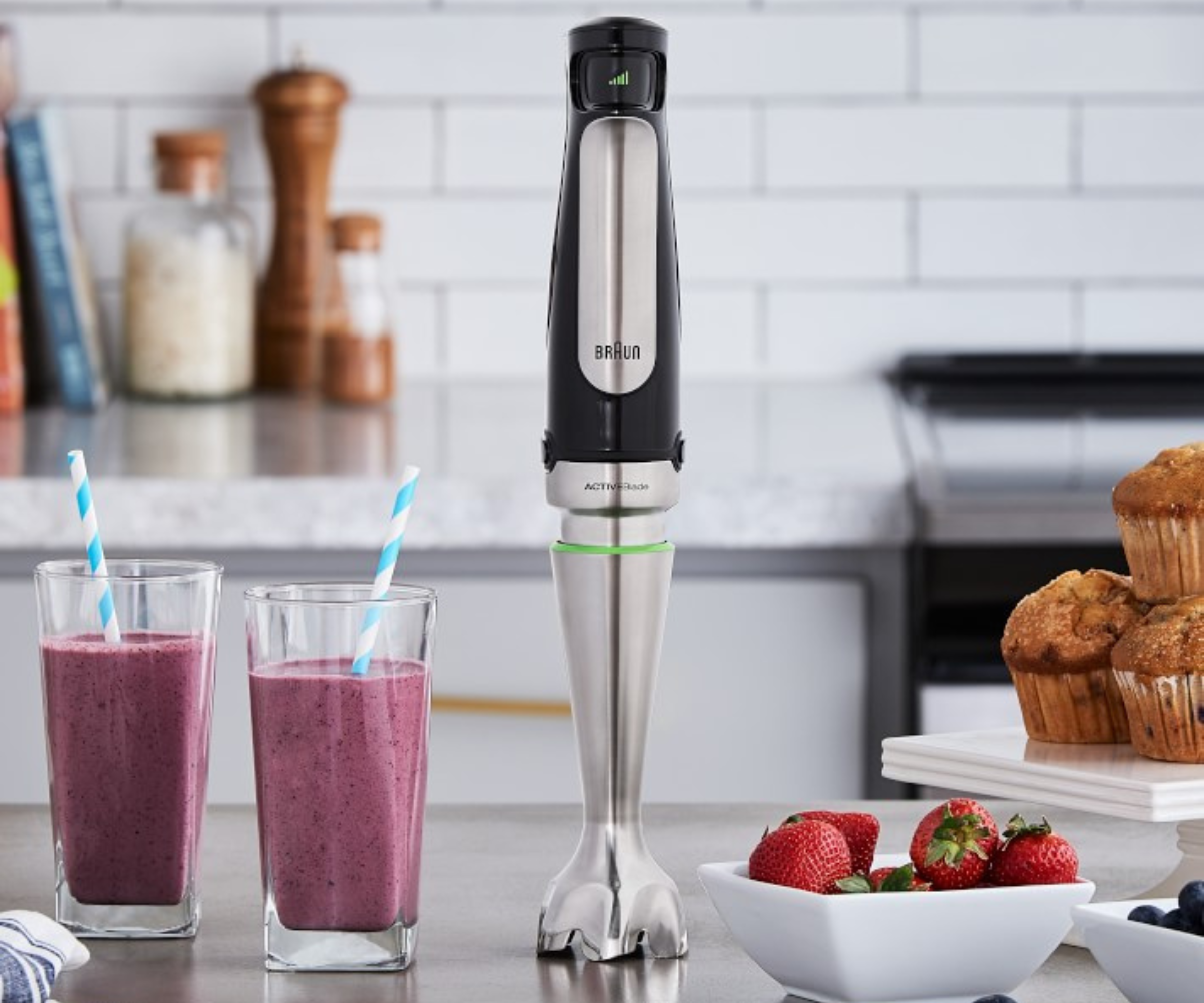 Braun immersion hand blender on a countertop next to smoothies and muffins