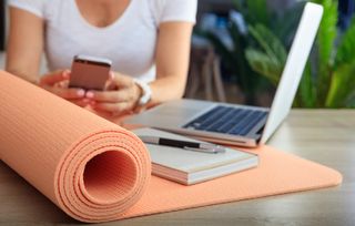 What time of day should I workout?: Woman and an exercise mat in an office background