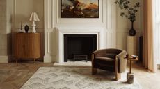 A living room with parquet flooring, a patterned rug, wainscoting, and a fireplace