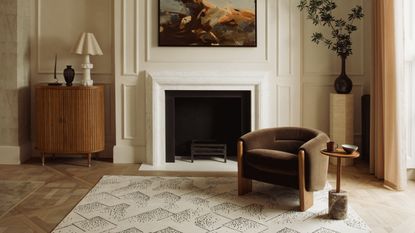 A living room with parquet flooring, a patterned rug, wainscoting, and a fireplace