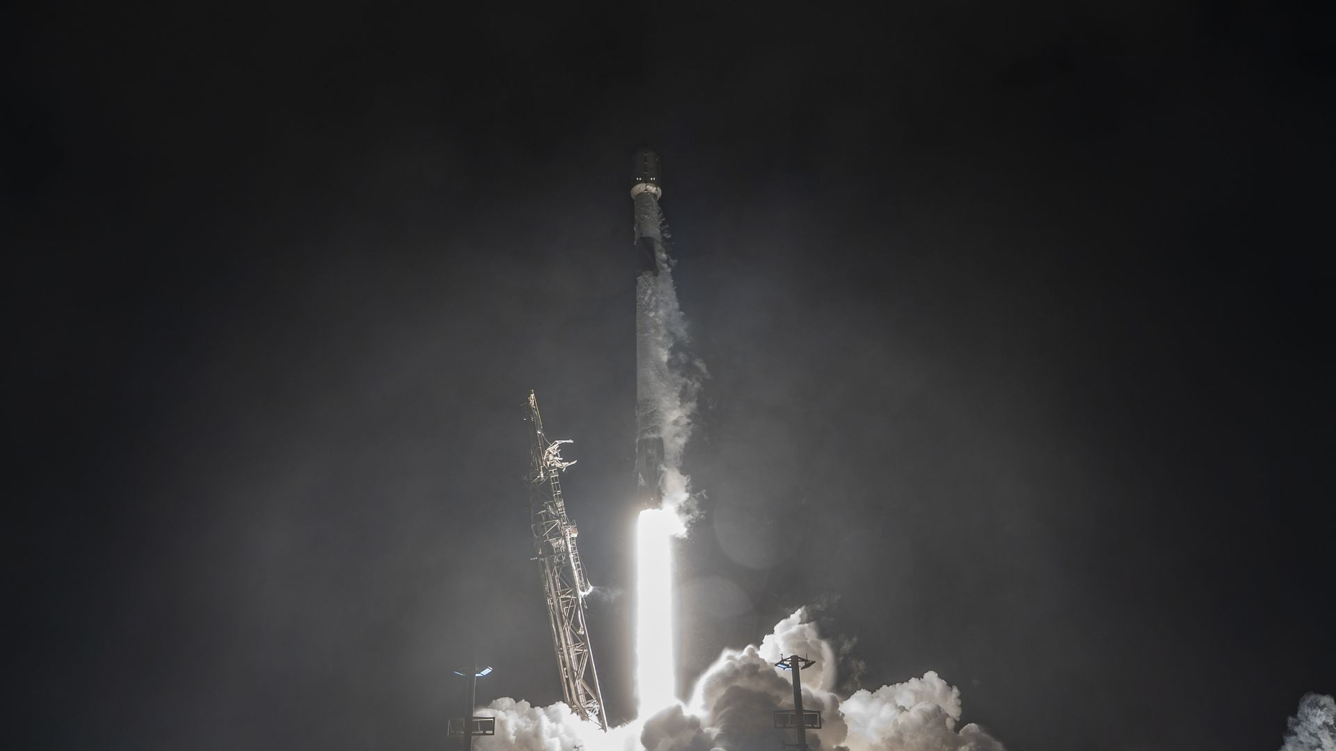 A white rocket blasts off in the dark of night.